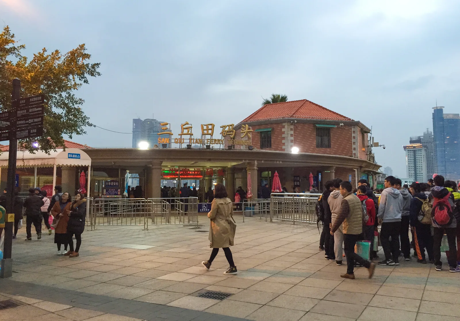 Travelers outside Sanqiutian Ferry Terminal on Gulangyu, with its Chinese and English sign
