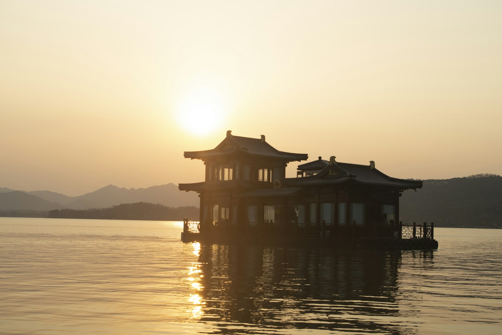 A traditional pavilion on Hangzhou’s West Lake in warm sunset light