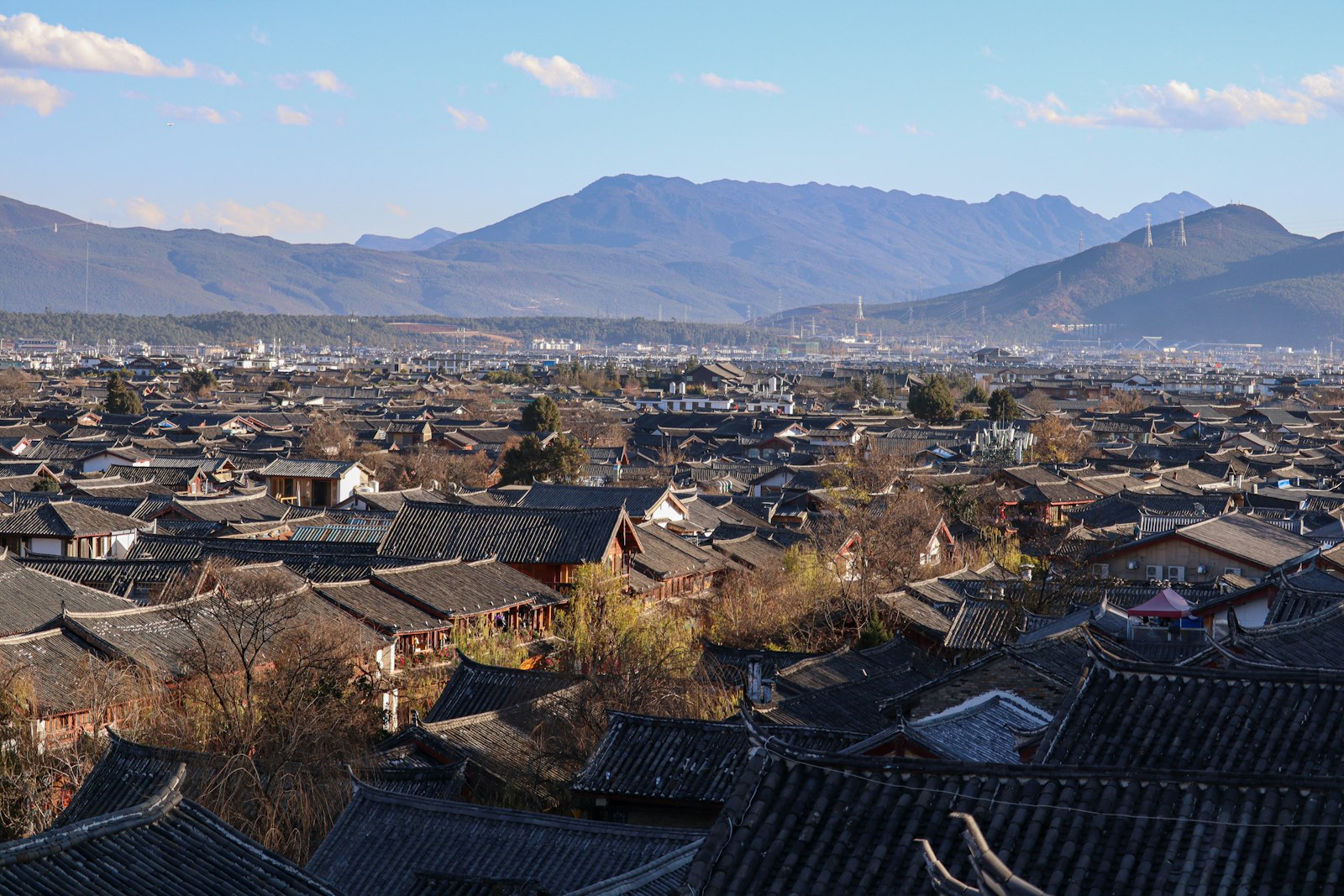 Lijiang’s old-town tiled rooftops beneath the surrounding mountain landscape
