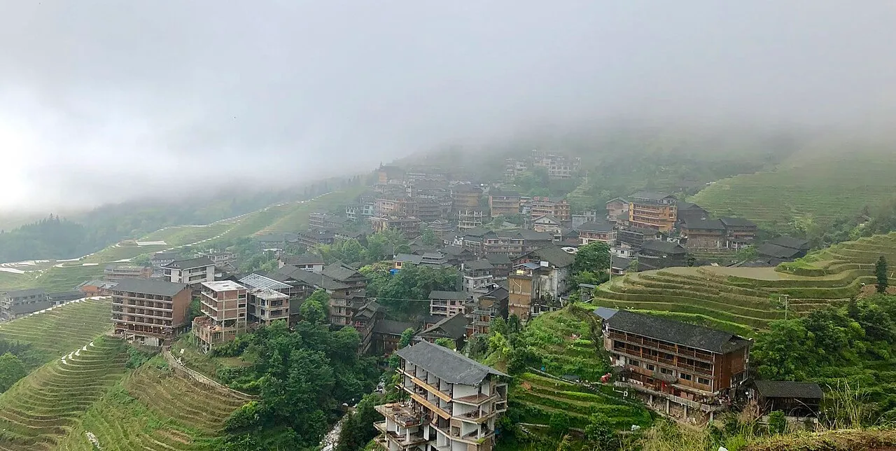 Pingan village buildings spread among terraced hillsides below low cloud
