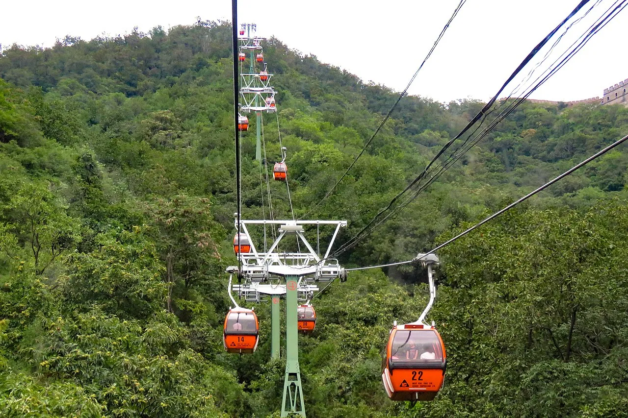 Enclosed red and yellow cable-car cabins above wooded slopes at Mutianyu